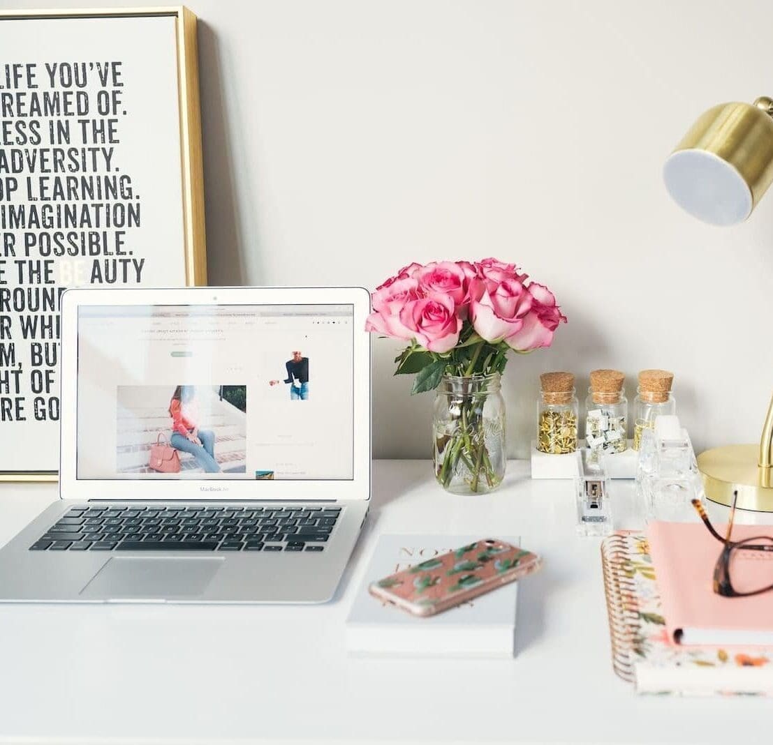 MacBook Air beside gold-colored study lamp and spiral books